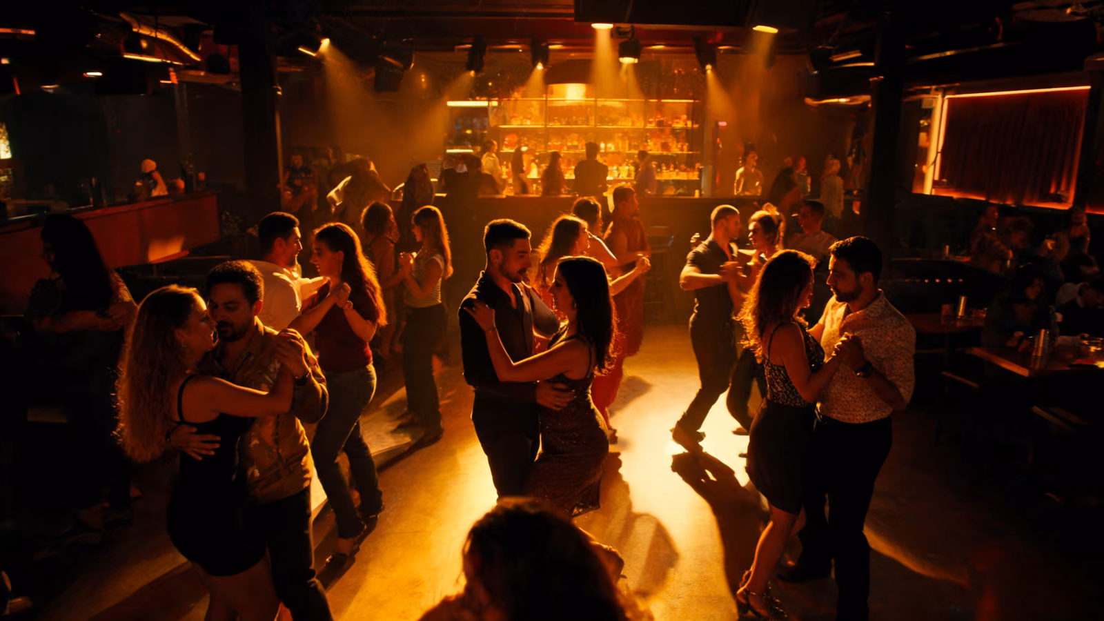 Pista de baile nocturna en Cali con parejas bailando salsa y luces cálidas